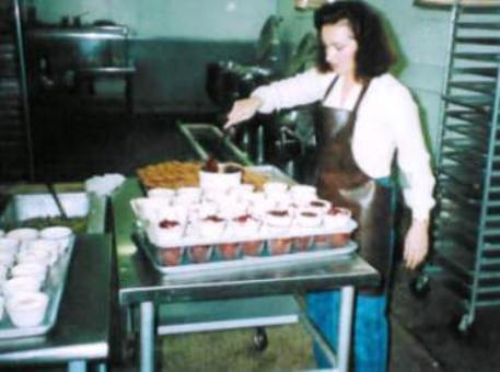 Jeanine Durand Arnopoulos prepping for lunch while in the background a display steam jacketed 40 gallon cookers line the back wall.